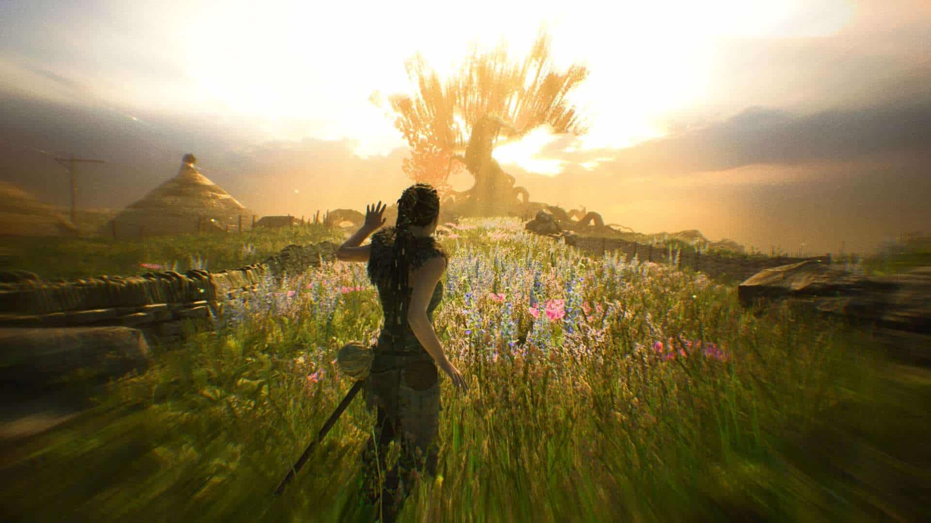 Hellblade: Senua's Sacrifice widoczne wspomnienie bohaterki, w którym zbliża się do drzewa pośrodku ukwieconej łąki. Kolory są przejaskrawione. Mitologia nordycka w grach wideo - to temat przewodni, bo Senua w drugiej części również eksploruje wikińskie klimaty.