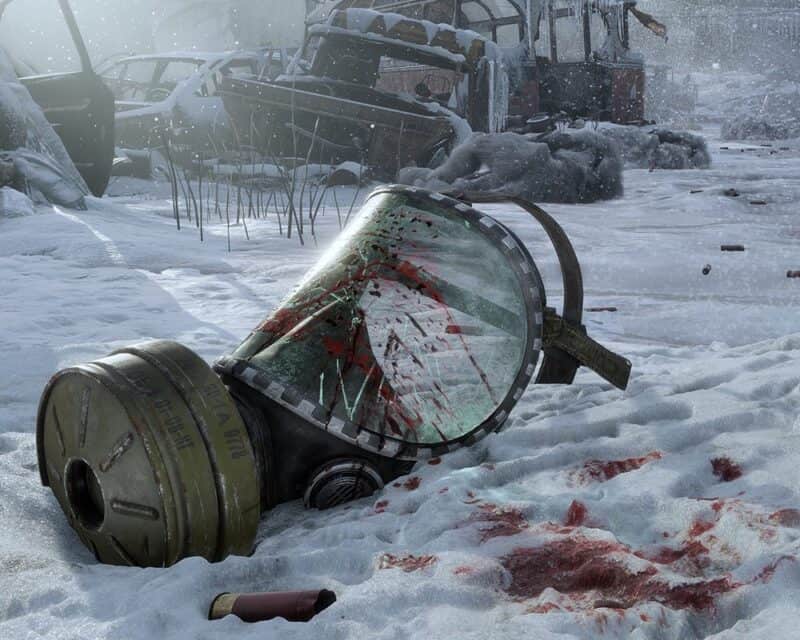 Screen z gry Metro Exodus - na śniegu leży zakrwawiona maska przeciwgazowa z pękniętą szybą. W tle widać wrak samochodu.