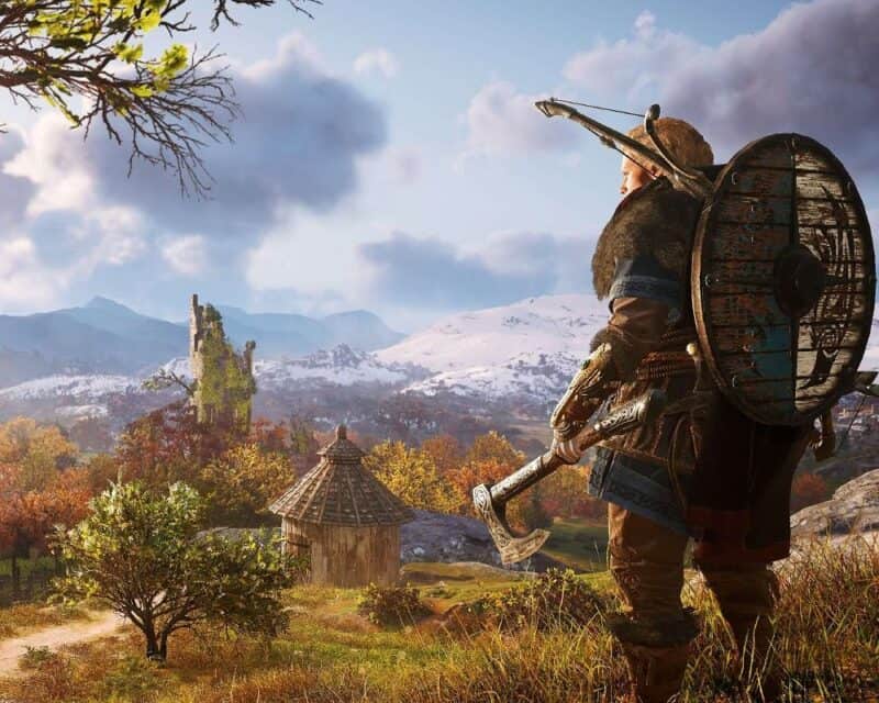 Assassin's Creed Valhalla, Irlandia w dodatku Gniew druidów, Eivor w plenerze z toporem w ręku i łukiem na plecach, w tle wieś i błękitne niebo
