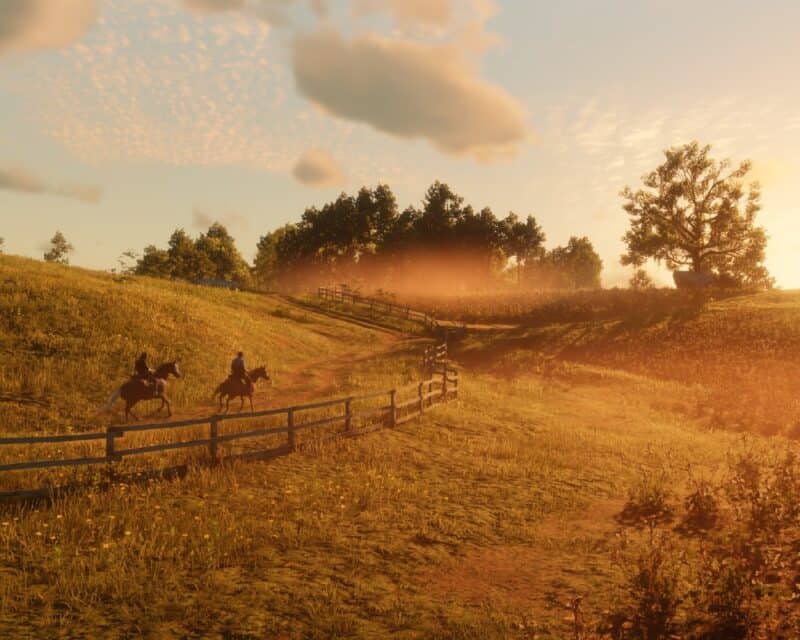 Screen z gry - zachód słońca, łąka, drzewo, dwie postacie na koniu -edukacja Red Dead Redemption 2
