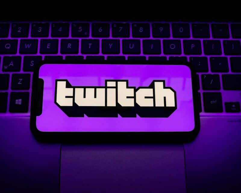 grafika przedstawiająca telefon z logo Twitch, w tle klawiatura, całość fioletowa, Twitch atak wyciek danych