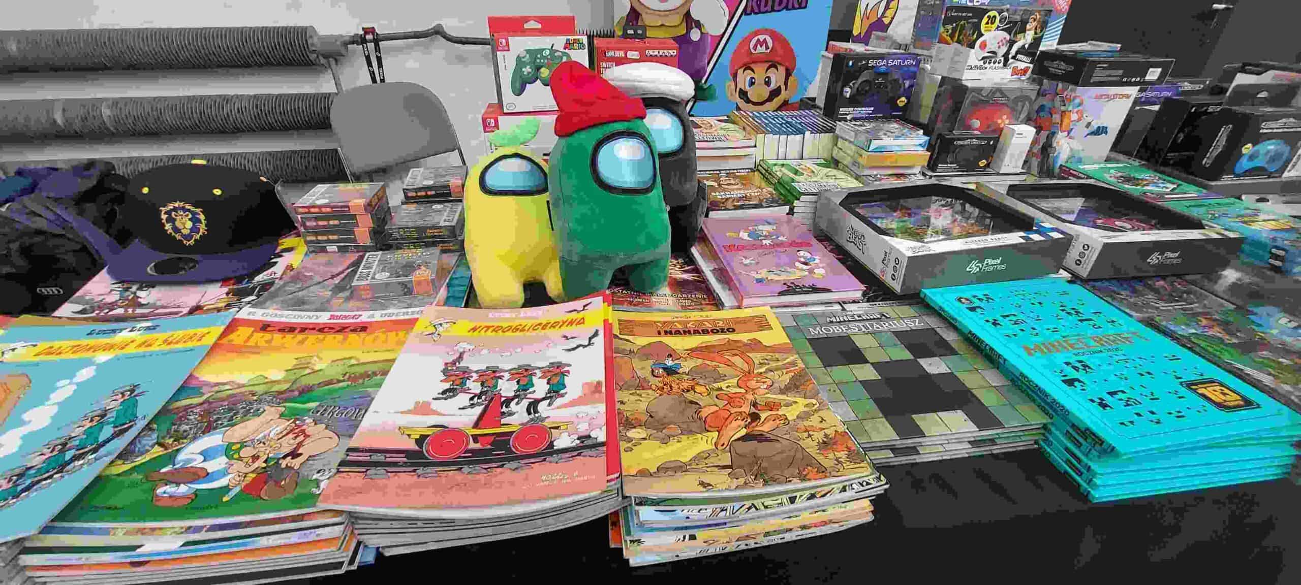 Stoisko z gadżetami, komiksami, widoczne postaci z Among Us