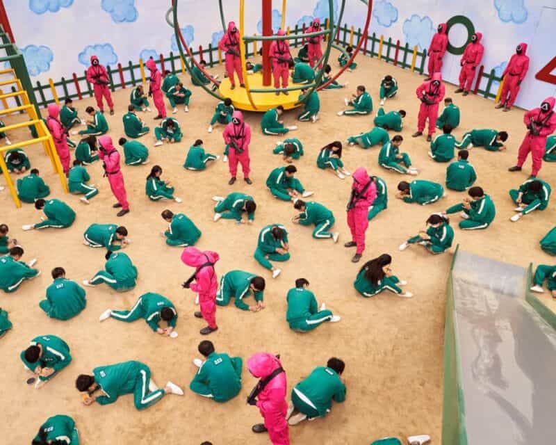 Gra komputerowa na podstawie Squid Game – jest taka możliwość – stopklatka z serialu, ludzie kucający i klęczący na placu zabaw (druga gra)