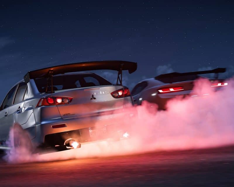 Grafika promująca grę Forza Horizon 5, przedstawia dwa samochody z tyłu, pierwszy srebny z lewej, drugi grafitowy w coupe, częściowo zasłonięty dymem wylatującym ze srebrnego auta, Forza Horizon 5 nowa aktualizacja