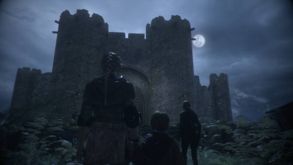 Screen z A Plague Tale: Innocence – Amicia i Hugo nocą na tle zamku