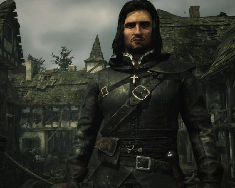 Ja Inkwizytor, screenshot ze zwiastuna gry, na obrazku w kolorach zieleni, brązu i czerni stoi mężczyzna w kapturze, na tle średniowiecznego miasteczka