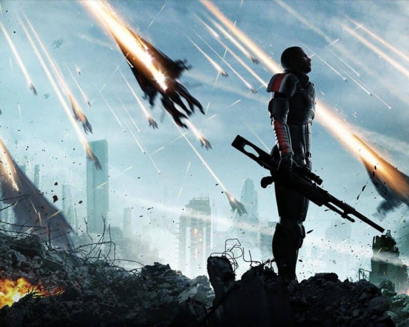 Mass Effect 3: Legendary Edition – mężczyzna w cieniu stojący bokiem patrzy w nasze prawo, do góry, dookoła niego i za nim ruiny, z nieba spadają duże maszyny, tak szybko że ciągnie się za nimi ognista łuna, ME3: LE recenzja