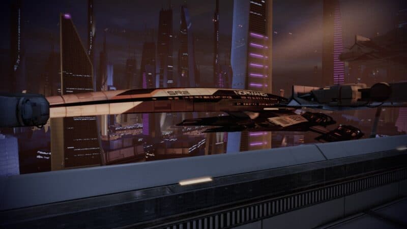 Mass Effect 2: Legendary Edition – Normandia stojąca w doku na Illium, widok lewej strony, w tle wieżowce