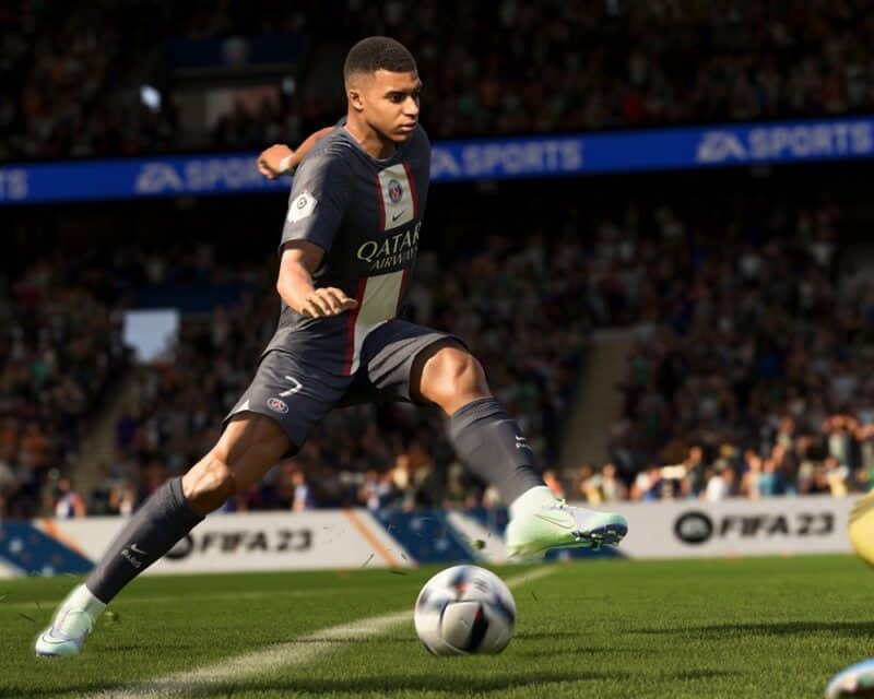 grafika przedstawiająca piłkarza atakującego bramkę przeciwnej drużyny, piłkarz o śniadej karnacji w granatowym stroju z białymi elementami (barwy drużyny Paris Saint-Germain), pod jego nogami piłka, w tle fragment stadionu i kibice, fifa 23 zwiastun