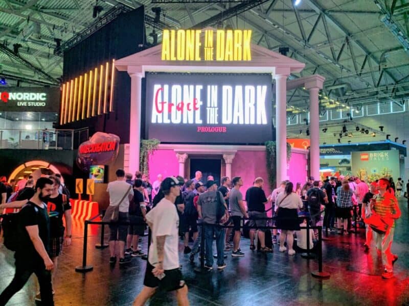 zdjęcie pochodzi ze strony jaxon.gg i przedstawia fragment dekoracji dla gry Alone in the Dark, ludzie stoją lub siedzą w kolejce do zagrania, wejście zdobią białe kolumny i zwisające po obu stronach pnącza