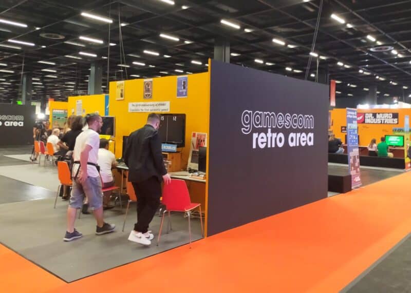 zdjęcie przedstawia fragment strefy retro na targach gamescom 2022, całość utrzymana w pomarańczowo-czarnych barwach, na czarnym tle widać napis "gamescom retro area"