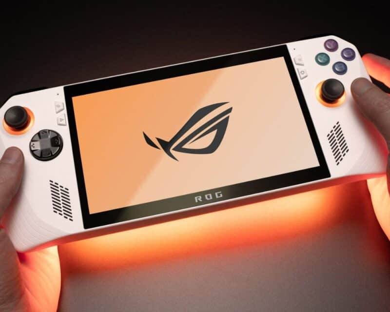 nowa przenośna konsola asus rog ally konkurent steam deck, na zdjęciu dłonie trzymające konsole z pomarańczowym podświetleniem od spodu i pomarańczową tapetą z logo Asus ROG