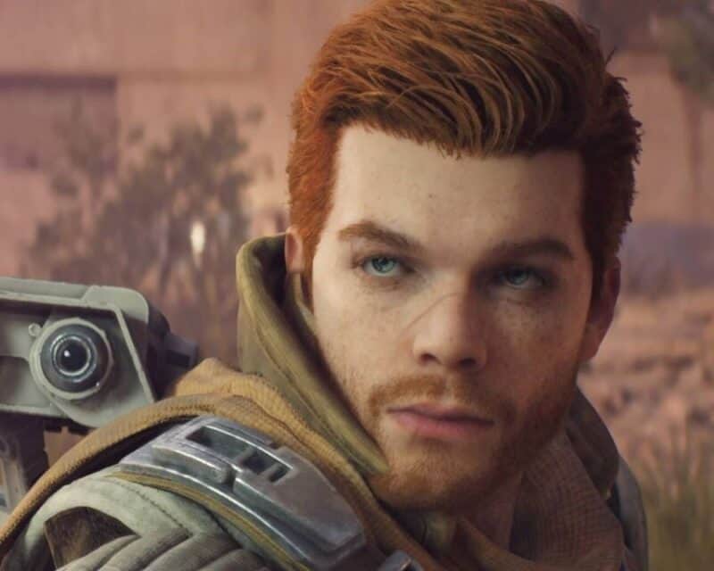 mężczyzna z rudymi włosami, na placach widać robota