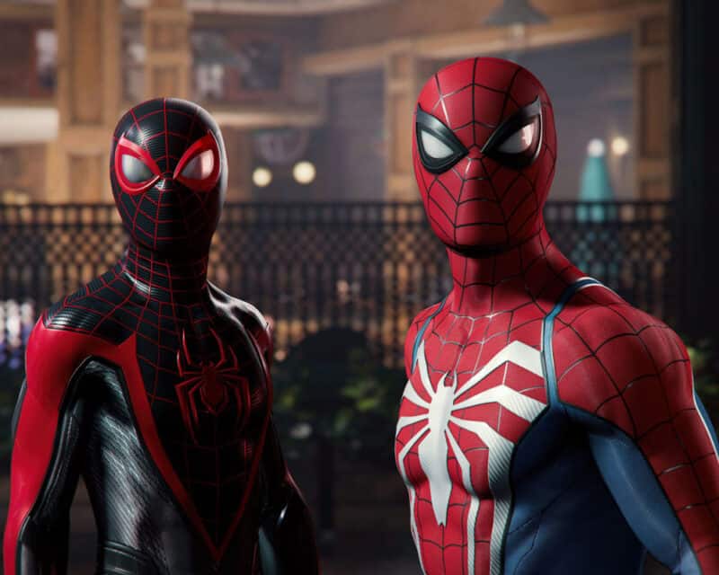 Dwójka Spider-Manów, Peter Parker i Miles Morales, spogląda w kamerę. W tle jest miejska sceneria.