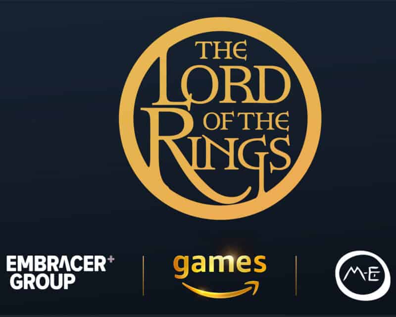 Obrazek przedstawia złote logo The Lord of the Rings na granatowym tle. Na dole grafiki znajdują się loga: Embracer Group, Amazon Games i Middle-earth Enterprises.