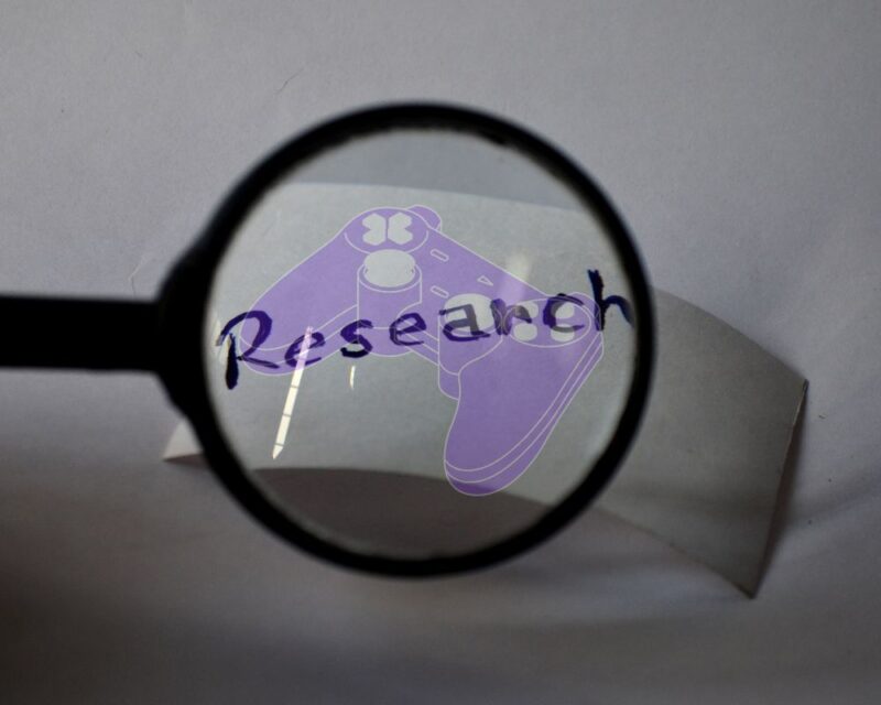 Pod szkłem lupy widoczny napis research a na nim półprzeźroczysty, fioletowy kontroler konsoli