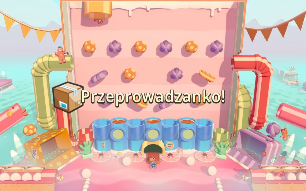 Screen z gry Moving Out 2. Obrazek przedstawia jeden z poziomów w grze – na różowej ścianie umieszczone są przeszkody w kolorach fioletowym i pomarańczowym. Obok widać rury prowadzące do ściany, a pod nią bohatera czekającego na rozpoczęcie rozgrywki. Na pierwszym planie widnieje napis "przeprowadzanko".