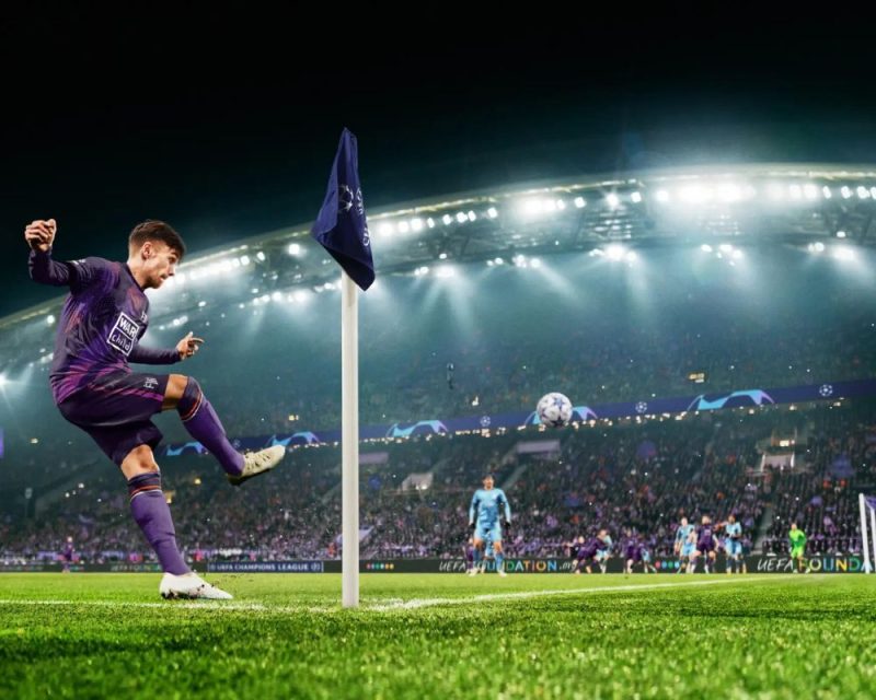 grafika z gry Football Manager 2024, przedstawia piłkarskie boisko w trakcie meczu, na pierwszym planie widzimy zawodnika w granatowo-bordowo-czarnym ubraniu, który wykonuje rzut rożny, obok słupek, z tyłu widać innych piłkarzy i trybuny