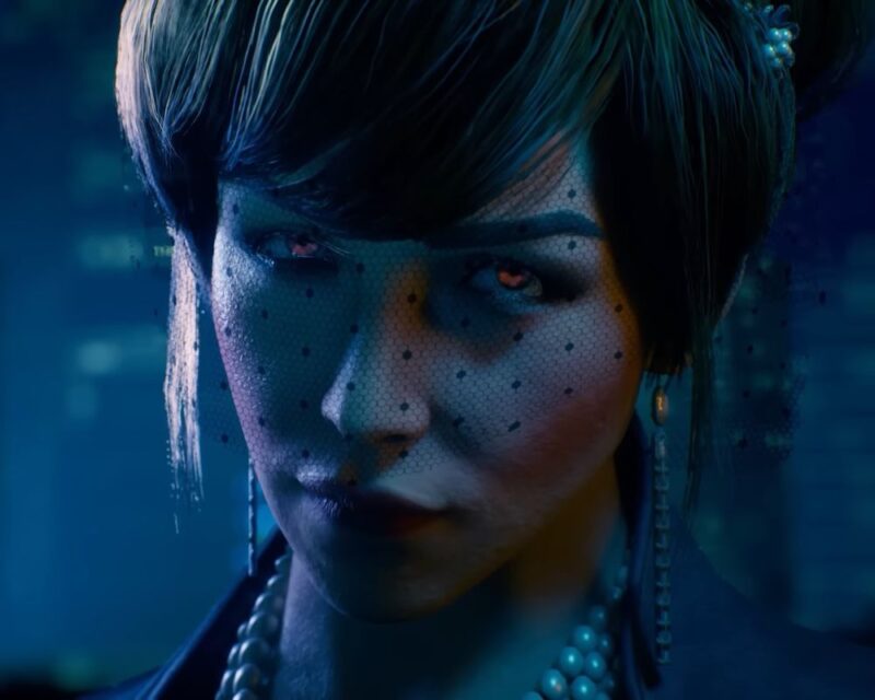grafika z zapowiedzi gry Vampire: The Masquerade – Bloodlines 2, przedstawia bladą kobietę o czerwonawych oczach i czarnych spiętych włosach, która ma na głowie czapkę z siateczką przesłaniającą połowę twarzy, na uszach kolczyki a na szyi naszyjnik z pereł