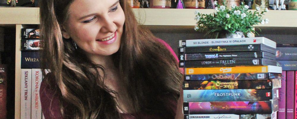 gra na prezent świąteczny, na zdjęciu dziewczyna z długimi włosami, trzyma w rękach stos gier PC w wydaniach pudełkowych