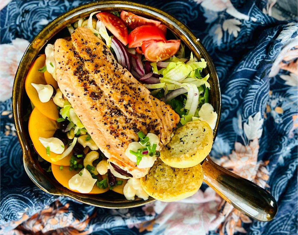 Avatar Frontiers of Pandora przepis sałatka, na zdjęciu widzimy sałatkę z łososiem smażonym,                        grzankami, sałatką, owocami i orzechami, podaną na patelni