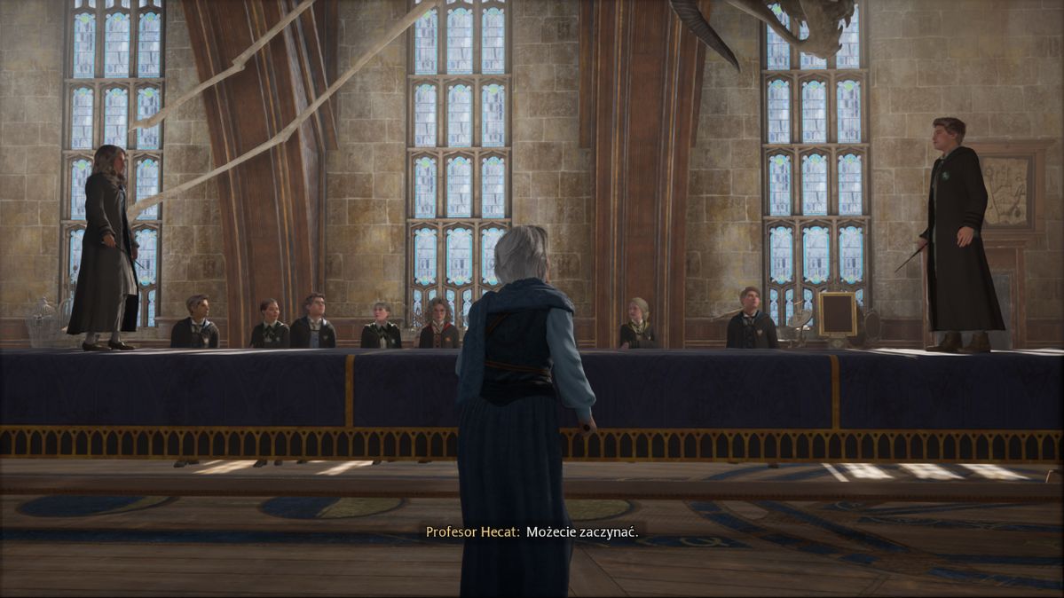 Hogwarts Legacy - nauka pojedynków, dwóch uczniów stoi na dwóch końcach specjalnego podium do walk magicznych, obok nauczycielka