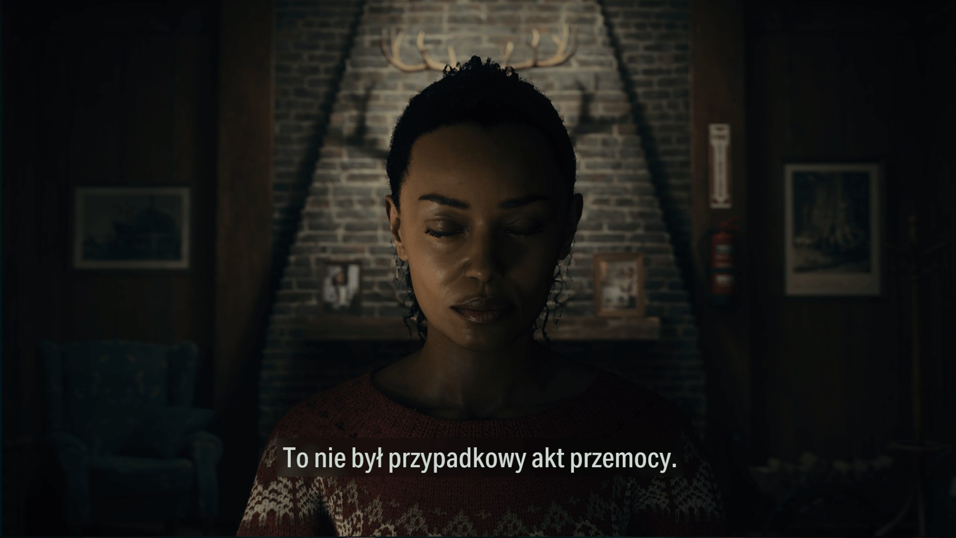 Zrzut ekranu z gry Alan Wake 2. Na obrazku widnieje kobieta, ma zamknięte oczy, jest na czymś skupiona. W tle widać ceglaną ścianę i wiszące na niej poroże. 