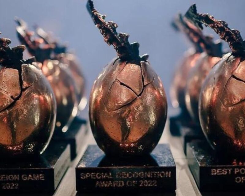 Zdjęcie przedstawia statuetkę Digital Dragons. Statuetka ma kształt jaja, z którego wystaje smoczy ogon.