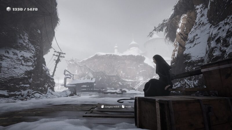 Indika siedzi na ławce, w tle zaśnieżona okolica.