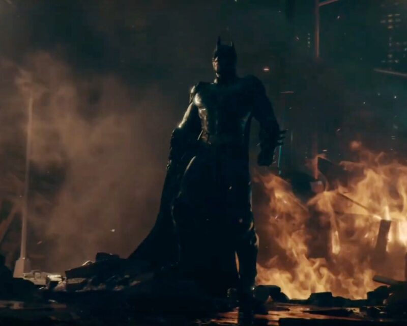 Zwiastun kinowy Batman Arkham Shadow Story – kadr z trailera, upozowany Batman stojący na tle pożogi