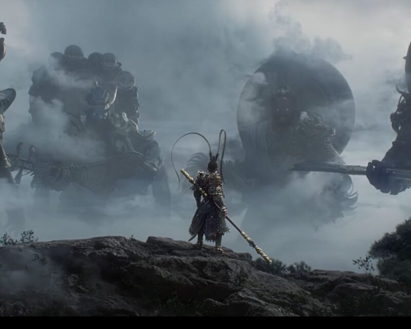 Główny bohater gry Małpi Król stoi na urwisku, trzymając broń. Ubrany jest w złotą zbroję, w dłoni trzyma kij. Przed nim z mgły wyłaniają się dwie, potężne postaci w chińskich, tradycyjnych maskach.