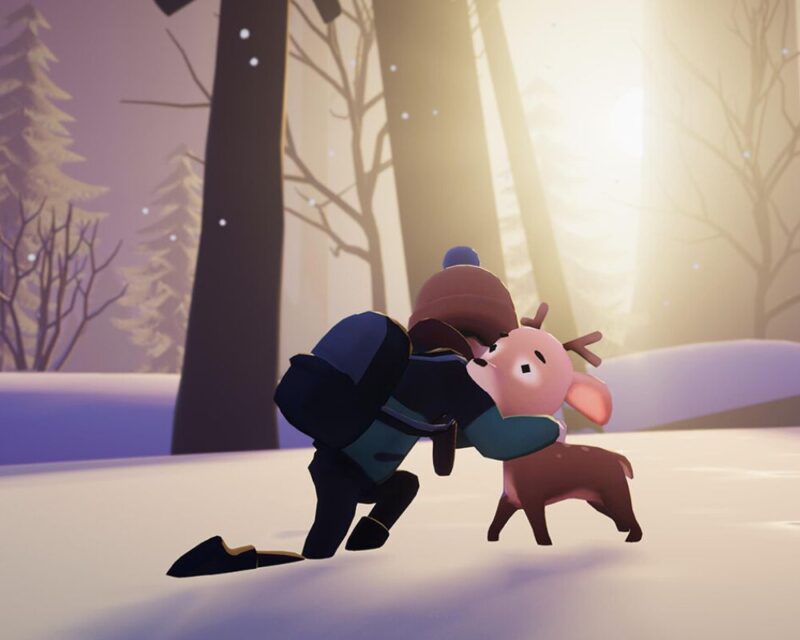 screenshot z gry Deer & Boy, widzimy na nim chłopczyka w zimowej kurtce i czapce, który tuli mlodego jelonka, stoją w śniegu, za nimi w tle pnie drzew, między ktorymi przeziera słońce
