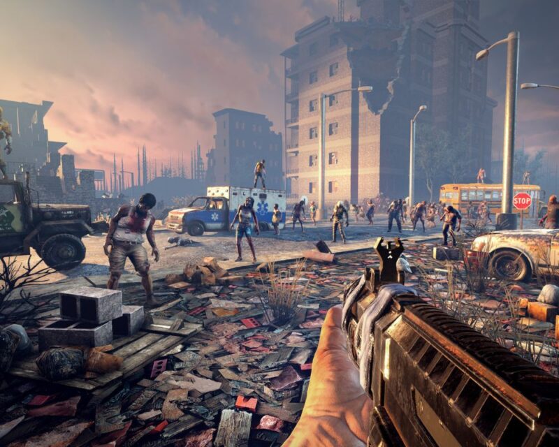 7 days to die, na grafice widzimy pierwszoosobową perspektywę z widoczną końcówką kolby pistoletu/karabinu/strzelby, która celuje w nadchodzące z oddali zombie, w tle widać ruiny miasta