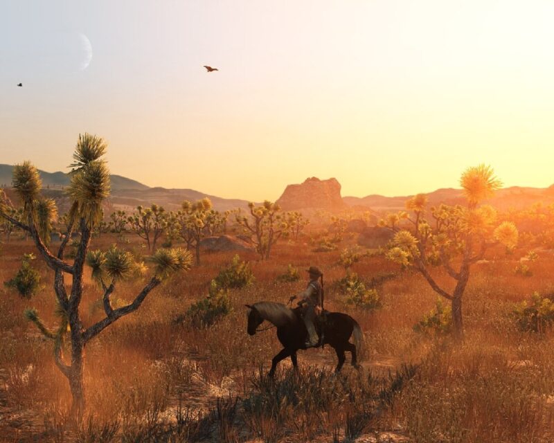 Piękna scena stepu porośniętego roślinnością, zachodzące słońce oraz główny bohater Red Dead Redemption jadący stępem na koniu, czyli kwintesencja dzikiego Zachodu, który już jutro dostanie port na PC
