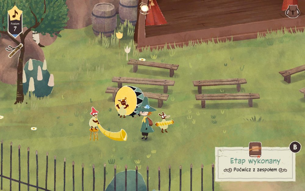 Grafika przedstawiająca bohaterów gry "Włóczykij: Melodia Doliny Muminków". Widzimy na niej lokalny teatr, ławki i Włóczykija.