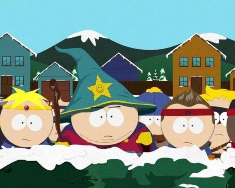 Kilku chłopców przebranych za czarodziejów stoi za krzakami.