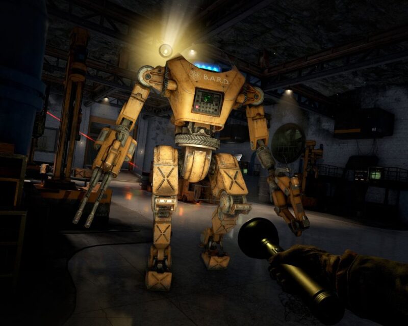 zrzut ekranu z gry Atomfall, widzimy żółtego robota z białym napisem B.A.R.D na przodzie, w prawym dolnym rogu widzimy dłoń sterowanej przez nas postaci trzymającą latarkę, dookoła jest ciemno, jedynie znad ramienia robota świeci mała lampka
