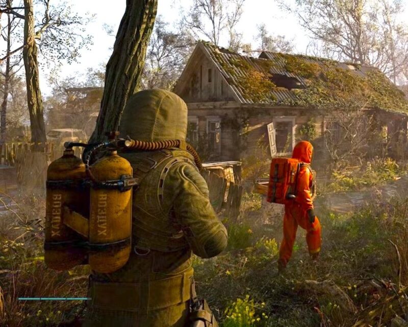 Dwóch postapokaliptycznych stalkerów eksploruje opuszczoną wioskę w zarośniętej strefie skażenia. Jeden z nich nosi zielony kombinezon z żółtymi butlami na plecach, a drugi pomarańczowy kombinezon ochronny. W tle widać zniszczony dom porośnięty roślinnością. Obraz pochodzi z gry STALKER 2: Heart of Chernobyl.