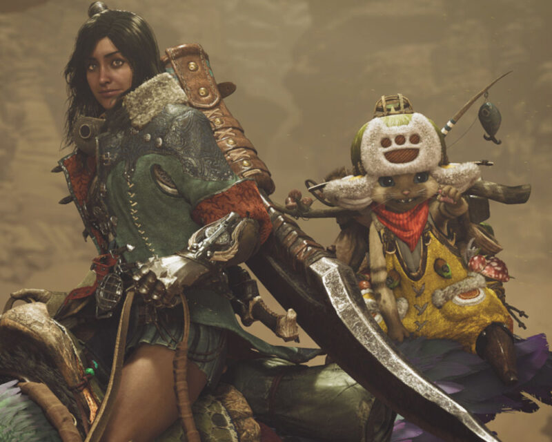 Na obrazku widać dwie postacie z gry Monster Hunter. Po lewej stronie znajduje się kobieta, która trzyma wielki miecz. Ma na sobie zielony płaszcz z futrzanym kołnierzem i skórzane spodnie. Jej twarz jest skupiona i wygląda na gotową do walki. Po prawej stronie znajduje się mała, antropomorficzna postać, przypominająca kota. Ma na sobie żółtą koszulkę i czerwony szalik. Na głowie ma czapkę z daszkiem i dużym, okrągłym znaczkiem. W ręku trzyma wędkę, na której zawieszona jest ryba. Obie postacie stoją na tle górzystego krajobrazu. Niebo jest zachmurzone i szare.