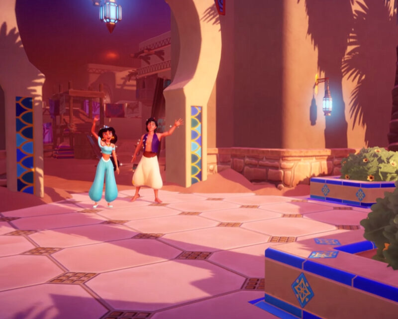 Na obrazku widać dwie postacie z filmu animowanego Disneya „Aladyn”: Dżasminę i Aladyna. Dżasmina jest po lewej stronie. Ma na sobie niebieski strój, typowy dla jej postaci. Jej włosy są ciemne i upięte. Aladyn stoi po prawej stronie. Również ma na sobie charakterystyczny strój, w tym fioletową kamizelkę i białe spodnie. Obie postacie są w pozycji stojącej i wydają się być w ruchu lub tańcu. Tło jest jasne i rozmyte, co skupia uwagę na postaciach.