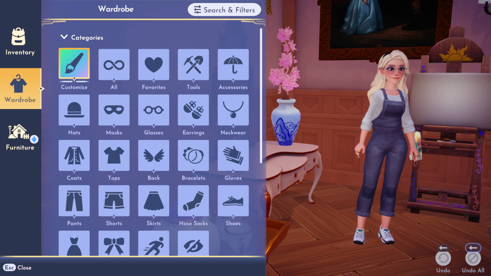Po lewej stronie znajduje się menu z trzema opcjami: "Inventory" (Ekwipunek), "Wardrobe" (Garderoba) i "Furniture" (Meble). Aktualnie zaznaczona jest opcja "Wardrobe".
W środkowej części ekranu widoczna jest postać kobieca, stojąca w pomieszczeniu. Kobieta ma blond włosy upięte w kok, nosi okulary przeciwsłoneczne, a ubrana jest w dżinsowy kombinezon i białe buty sportowe. W tle widać fragment obrazu z przedstawioną postacią w niebieskiej sukni, stojący na sztalugach obraz oraz wazon z kwiatami.
Po prawej stronie znajduje się menu "Wardrobe" z różnymi kategoriami ubrań i akcesoriów, takimi jak "Hats" (Kapelusze), "Masks" (Maski), "Glasses" (Okulary), "Earrings" (Kolczyki), "Neckwear" (Ozdoby na szyję), "Coats" (Płaszcze), "Tops" (Góra), "Back" (Tył), "Bracelets" (Bransoletki), "Gloves" (Rękawiczki), "Pants" (Spodnie), "Shorts" (Szorty), "Skirts" (Spódnice), "Hose Socks" (Rajstopy i Skarpety) oraz "Shoes" (Buty). W dolnej części menu znajdują się ikony przedstawiające różne funkcje, takie jak "Undo" (Cofnij) i "Undo All" (Cofnij wszystko).
W górnej części ekranu widoczne są napisy "Wardrobe" oraz "Search & Filters" (Szukaj i Filtry).