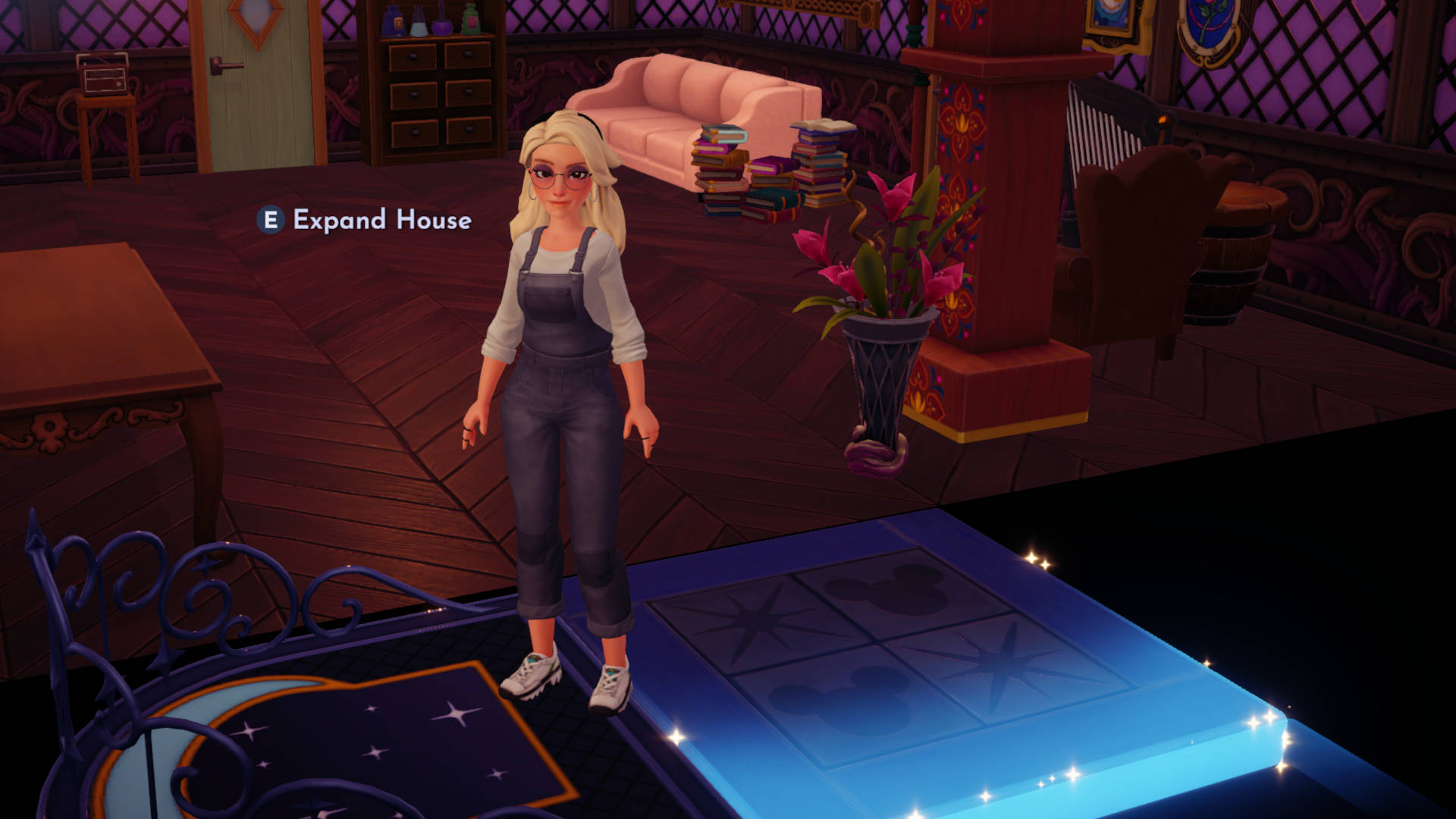 Postać gracza: Na pierwszym planie znajduje się postać gracza, kobieta o blond włosach, ubrana w szare ogrodniczki i białe buty sportowe.
Wnętrze domu: Scena rozgrywa się we wnętrzu domu gracza. W tle widać różne meble:
Różową sofę z ułożonymi na niej stosami książek.
Drewnianą szafkę z półkami.
Ciemny, ozdobny fotel.
Wazon z różowymi kwiatami.
Podłoga: Podłoga wykonana jest z ciemnych, drewnianych desek.
Dywan: Na podłodze leży okrągły dywan z motywem księżyca i gwiazd.
Interakcja: Nad postacią gracza widoczny jest napis "E Expand House", co wskazuje na możliwość rozbudowy domu.
Elementy dekoracyjne: W tle widać również ozdobne kolumny i inne elementy dekoracyjne, które nadają wnętrzu przytulny charakter.
Oświetlenie: Oświetlenie w pomieszczeniu jest ciepłe i stonowane, co tworzy przyjemną atmosferę.
Stolik: Na pierwszym planie widoczny jest stolik z niebieską, świecącą górą.
