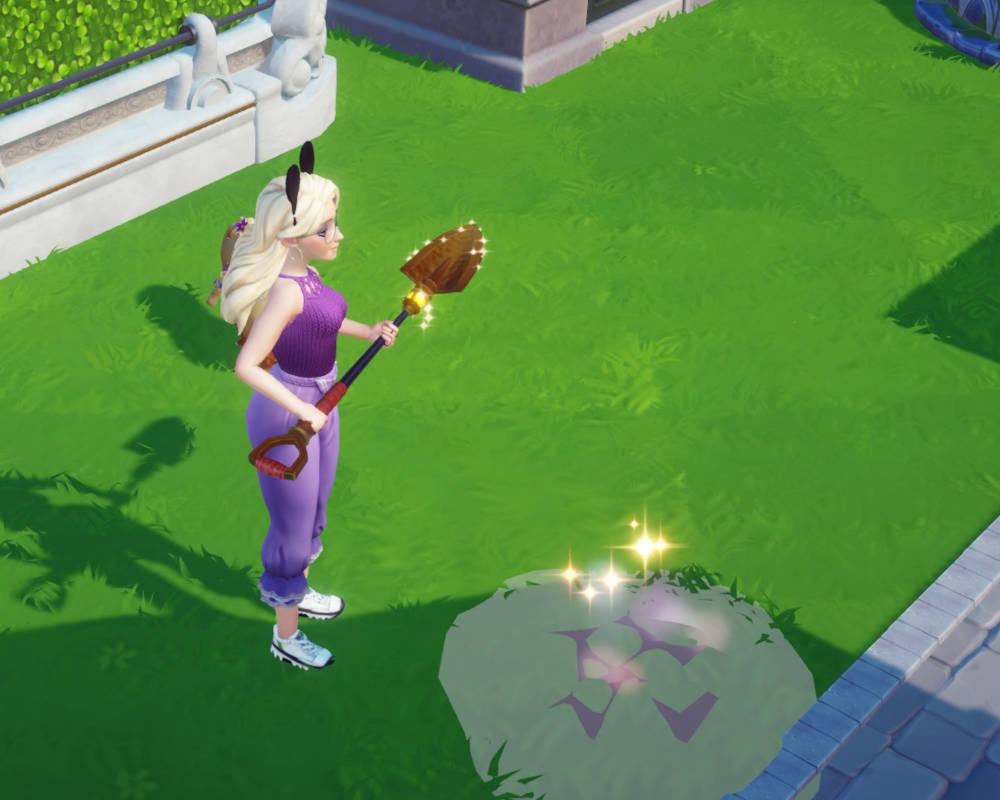 Główny element obrazu to postać kobieca, widziana z perspektywy trzeciej osoby, z góry i nieco z boku. Postać ma jasne włosy, które są spięte w kucyk i ozdobione czarnymi uszami (prawdopodobnie kocimi lub króliczymi). Ubrana jest w fioletowy top na ramiączkach i fioletowe spodnie typu "baggy". Na nogach ma białe buty sportowe.

W rękach postać trzyma łopatę, sugerującą, że wykonuje jakąś pracę lub czynność związaną z kopaniem lub uprawą ziemi.

Na ziemi, tuż przed postacią, znajduje się kępa trawy z połyskującymi elementami i fioletowymi symbolami. Może to oznaczać miejsce, w którym postać ma wykonać akcję za pomocą łopaty, np. wykopać skarb, posadzić roślinę lub usunąć przeszkodę.

Tło obrazu jest zielone, z widocznymi elementami muru lub ogrodzenia. W lewym górnym rogu widzimy fragment białego muru z zielonym żywopłotem i białymi rzeźbami (prawdopodobnie lwami). W prawym górnym rogu znajduje się fragment budynku z szarymi elementami i niebieskim dachem lub krawędzią.

Grafika gry jest kolorowa i kreskówkowa, co sugeruje, że jest to gra skierowana do młodszej publiczności lub o lekkiej, relaksującej tematyce.

Ogólny nastrój obrazu jest spokojny i pozytywny, z elementami magii lub fantazji, sugerowanymi przez uszy postaci i połyskujące elementy na ziemi.