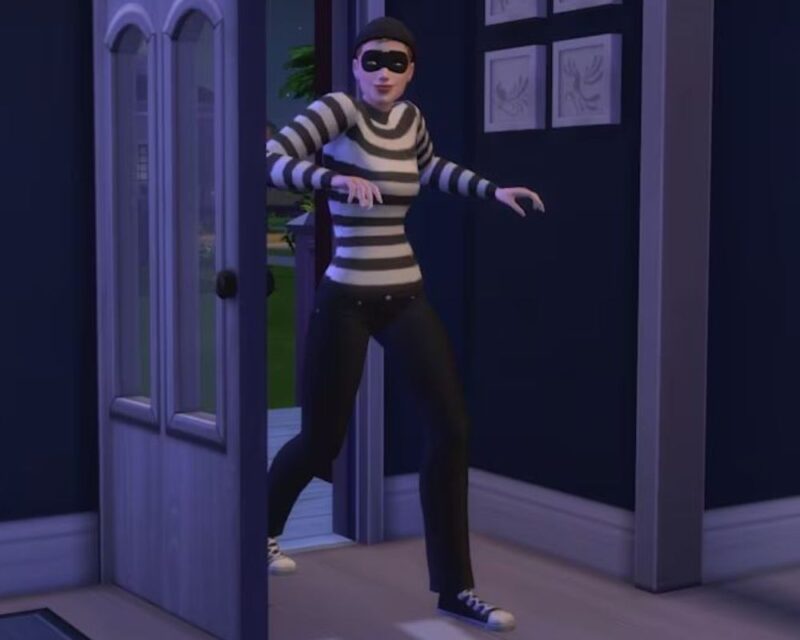 Postać ubrana w czarno-białą pasiastą koszulkę, czarne spodnie i czapkę stoi w uchylonych drzwiach. Ma na twarzy czarną maskę na oczy i przyjmuje skuloną postawę, jakby zakradała się do środka. Scena jest oświetlona nocnym światłem, a wystrój wnętrza sugeruje, że to dom.