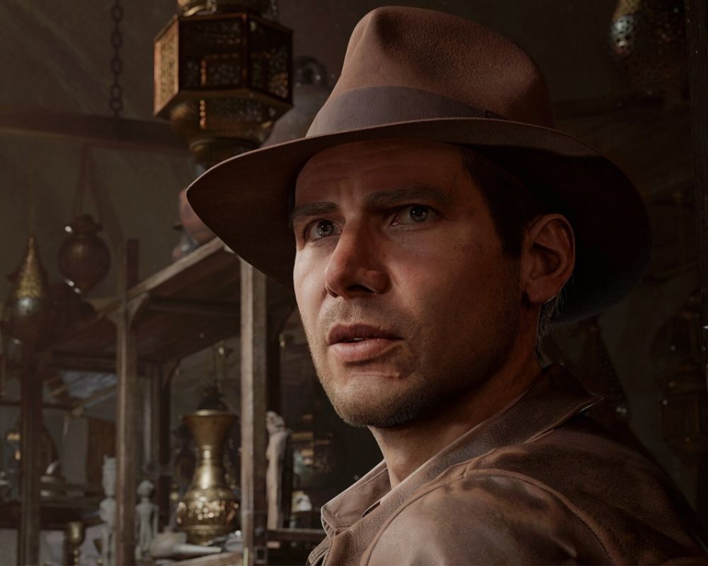 Obrazek przedstawia mężczyznę w kapeluszu i skórzanej kurtce. Jego twarz ma skupiony wyraz, jakby znajdował się w napiętej sytuacji. W tle widać półki z różnymi antykami i orientalnymi lampami, co sugeruje, że może być w sklepie z antykami lub na bazarze.