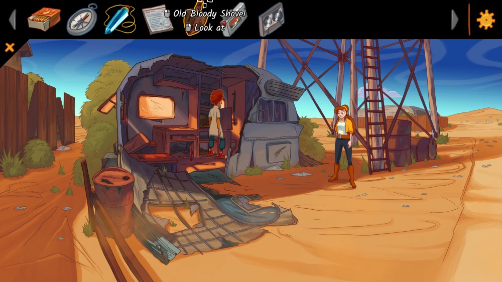 Scena z gry "Elroy and the Aliens". Elroy przeszukuje wnętrze zniszczonej przyczepy stojącej na skraju pustyni, oświetlonej ciepłym, zachodzącym słońcem. W środku widać stare półki i porozrzucane przedmioty. Przed przyczepą Peggie stoi uśmiechnięta obok metalowej konstrukcji wieży ciśnień, otoczona pustynnym krajobrazem, beczkami i piaskiem. Na górze ekranu widoczny jest interfejs gry z ikonami przedmiotów, w tym zakrwawioną łopatą.