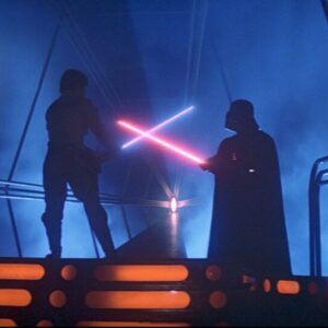 Kadr z filmu Gwiezdne Wojny: Powrót Jedi, dwóch mężczyzn walczy na miecze świetlne, jeden ma na sobie czarną zbroję i hełm, w rękach czerwony miecz świetlny, drugi zaś jest uzbrojony w niebieski miecz