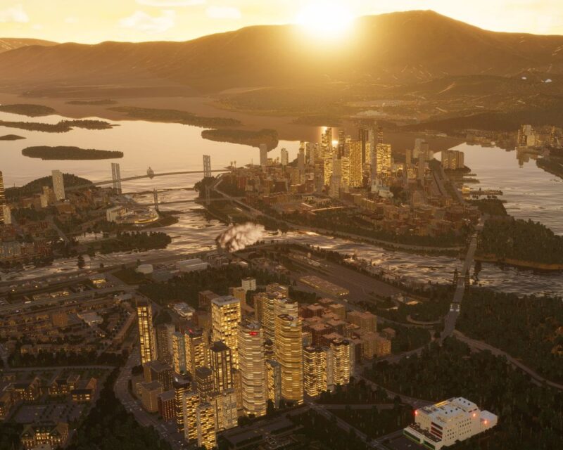 Obrazek przedstawia nowoczesne miasto o zachodzie słońca, z wieloma wieżowcami, mostami i wodą otaczającą centrum. W tle widać góry i zachodzące słońce.