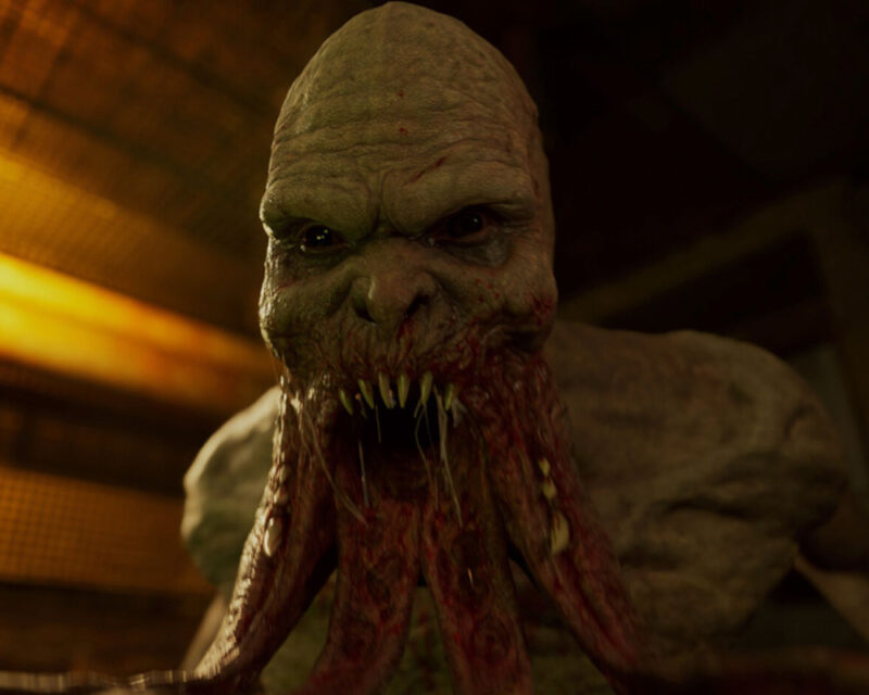 Na pierwszym planie widzimy przerażającą kreaturę, która wydaje się być hybrydą humanoida i jakiegoś bliżej nieokreślonego potwora. Jej skóra jest blada, o nierównej teksturze, pokryta drobnymi wypustkami i żyłkami. Twarz jest zdeformowana, z małymi, ciemnymi oczami osadzonymi głęboko pod wydatnymi łukami brwiowymi. Nos jest spłaszczony i niemal niewidoczny, a usta rozwarte, ukazując rzędy ostrych, nieregularnych zębów. Z dolnej części twarzy wyrastają liczne, mięsiste macki o czerwonawej barwie, które wyglądają na oślizgłe i krwiste. Kreatura wydaje się być zwrócona bezpośrednio w stronę obserwatora, co potęguje uczucie zagrożenia i konfrontacji. Jej wyraz twarzy jest agresywny i drapieżny. Tło jest ciemne i nieostre, sugerując, że akcja rozgrywa się w jakimś zamkniętym, mrocznym pomieszczeniu lub tunelu. Można dostrzec fragmenty jakiejś metalowej konstrukcji lub kraty, co dodatkowo buduje klaustrofobiczną i niebezpieczną atmosferę. Oświetlenie jest skierowane na potwora, co sprawia, że jego przerażające detale są dobrze widoczne, a reszta otoczenia pozostaje w cieniu. Kontrast między jasną postacią a ciemnym tłem wzmacnia dramatyzm sceny. Ogólnie rzecz biorąc, obrazek wywołuje uczucie grozy, niepokoju i obrzydzenia. Przedstawiona kreatura jest odrażająca i budzi strach. Biorąc pod uwagę Twoją sugestię, że może to być związane z grą S.T.A.L.K.E.R. 2: Heart of Chornobyl, przedstawiona istota przypomina niektóre z mutantów znanych z tej serii, charakteryzujących się zdeformowanymi ciałami i agresywnym zachowaniem w postapokaliptycznej Zonie.