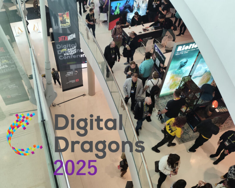 Ujęcie z góry na halę konferencyjną Digital Dragons 2025, gdzie ludzie poruszają się między stoiskami wystawców, z widocznymi banerami reklamowymi i logo wydarzenia na pierwszym planie. Relacja z Digital Dragons 2025